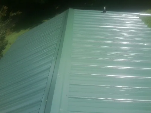 New green metal panels meeting at the ridge of a roof — Flat Roof Repair work by our crew in Oxford
